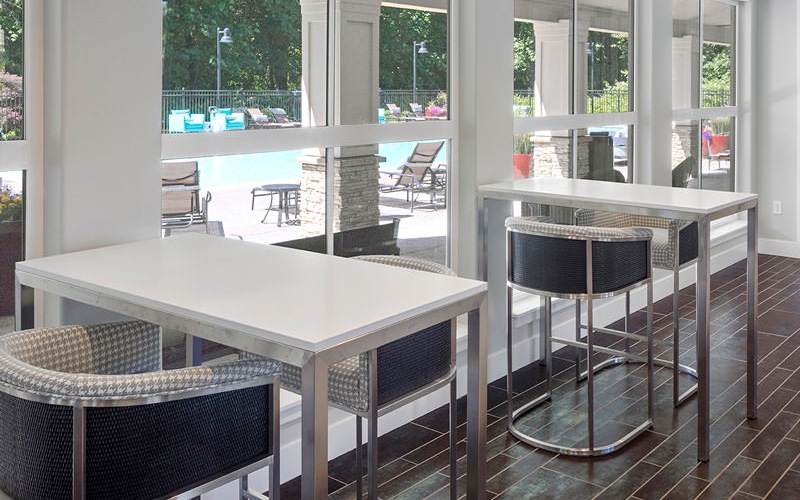 high tables and chairs in resident lounge near windows with pool views