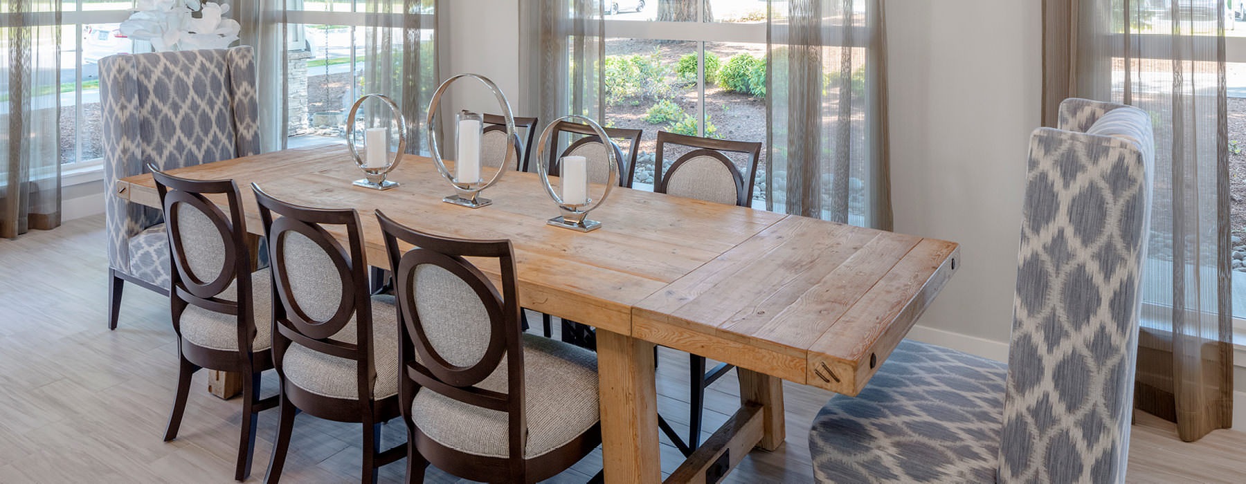 long table surrounded by chairs and windows in resident lounge